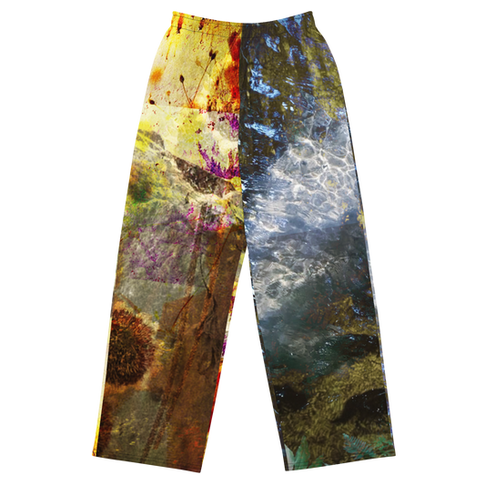 A pair of wide-leg pants featuring a split abstract design: one leg has a yellow, brown, and purple paint-splatter pattern, while the other leg has a blue, gray, and white water-like pattern, shown against a plain white background.