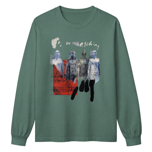 A sage green long-sleeve t-shirt with a graphic print on the front. The graphic features the word 'watching' in a distressed white font above a collage of four figures in blue, gray, and black tones, with a red textured block on the left side.