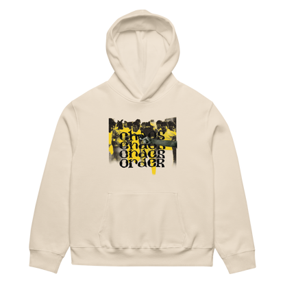 A cream-colored pullover hoodie with a front kangaroo pocket and a central graphic print featuring a black-and-white crowd scene with bold yellow and black text reading 'ONE CHARGE ORDER'.