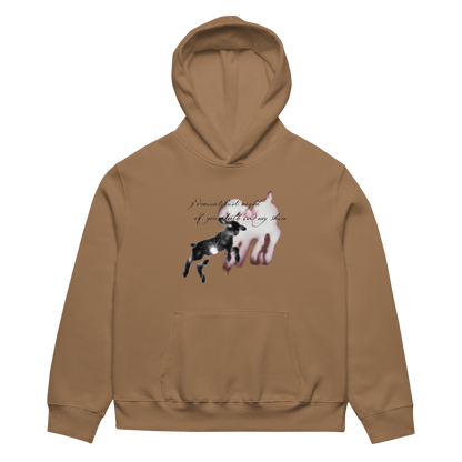 A tan hoodie shown flat against a white background, featuring a graphic print on the chest with a black goat, a white goat silhouette, and cursive text.